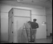 DESCRIPTION TE2/1977/3nExhibition installation. Begins with a cut and zoom that reveals an elongated gallery space being filmed with a handheld camera. There is a neon-lit arrow on the opposite wall. Two men are conversing and installing parts of an exhibition as the camera pans, zooms, and is carried about the room. There are sounds of construction, indiscernible conversation, and whistling as the camera continues to move around the gallery space. The focus of this footage appears to be 3 men i