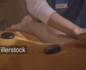 Massage therapist is massaging a female leg using hot stones.nLicense this clip: https://fillerstock.com/video/3746