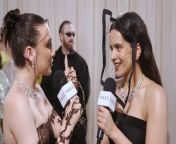 Rosalía talks with Emma Chamberlain at the 2024 Met Gala about her unique Stephen Jones headpiece and her incredibly tight corset.
